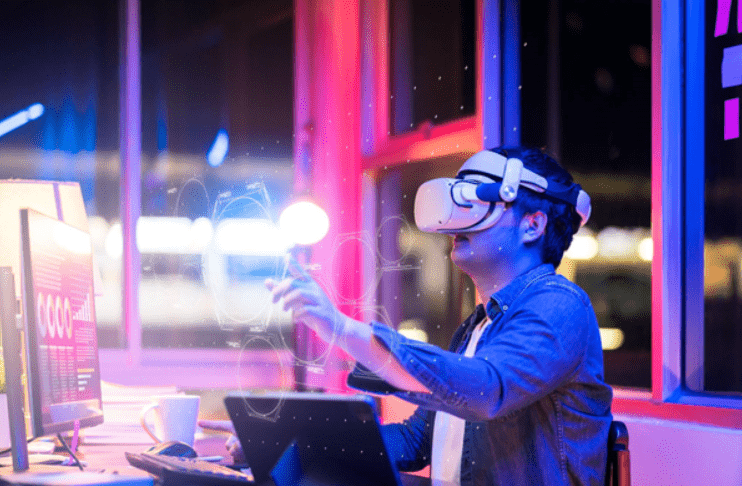Imagem ilustrativa de Homem com Óculos de realidade virtual. Na imagem, um homem está sentado em uma mesa de computador, com roupas sociais, assistindo algo através dos Óculos.